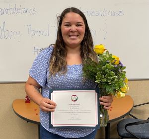 Brooklynn Garza poses with her Caring Hearts certificate and a vase with yellow roses.