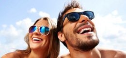 A man and a woman smile at the beach.