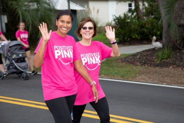 Walkers wearing "positively pin" T-shirts wave as they participate in the In the Pink breast cancer awareness walk.