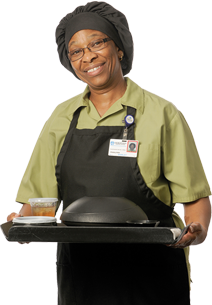 A helpful cafeteria employee smiling with a trey of food.