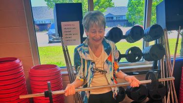 Patricia Pahmeier grips a dumbell with both hands as she lifts it toward her chest during a Power Thru Parkinson's class at the YMCA.