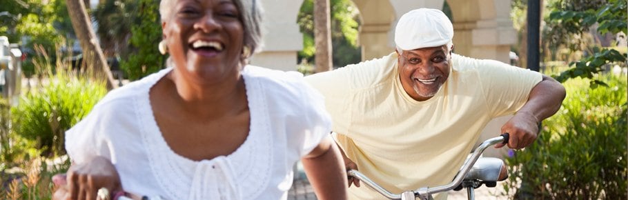 A couple riding bicycles together and laughing.