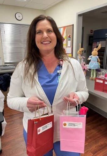 Bobbie Stewart smiles as she holds a gift bag in each hand.