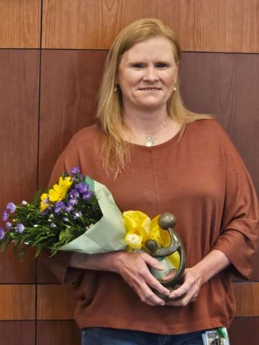 Cheryl Richardson holding flowers and the Daisy award statue