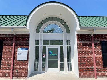 exterior of the entrance to Tidelands Health Family Medicine at Murrells Inlet, with the Tidelands Health blue and green logo on the glass door